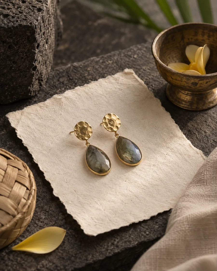 Drop earrings on handmade paper beside a Balinese brass bowl